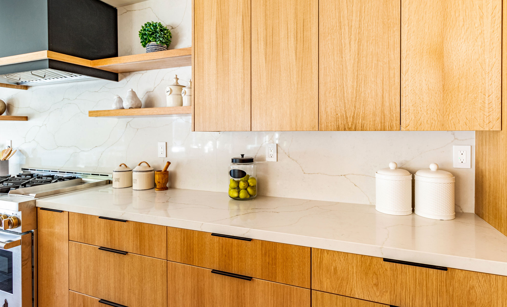 A bright kitchen has warm wood cabinets and quartz countertops, resulting in a natural and cohesive look throughout the space.