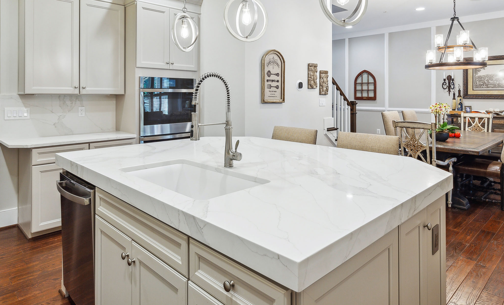 Alt Text: This image depicts a sleek, modern kitchen featuring a large, minimalist quartz island in soft, neutral tones. The island has clean lines and subtle veining, blending with the kitchen's design.